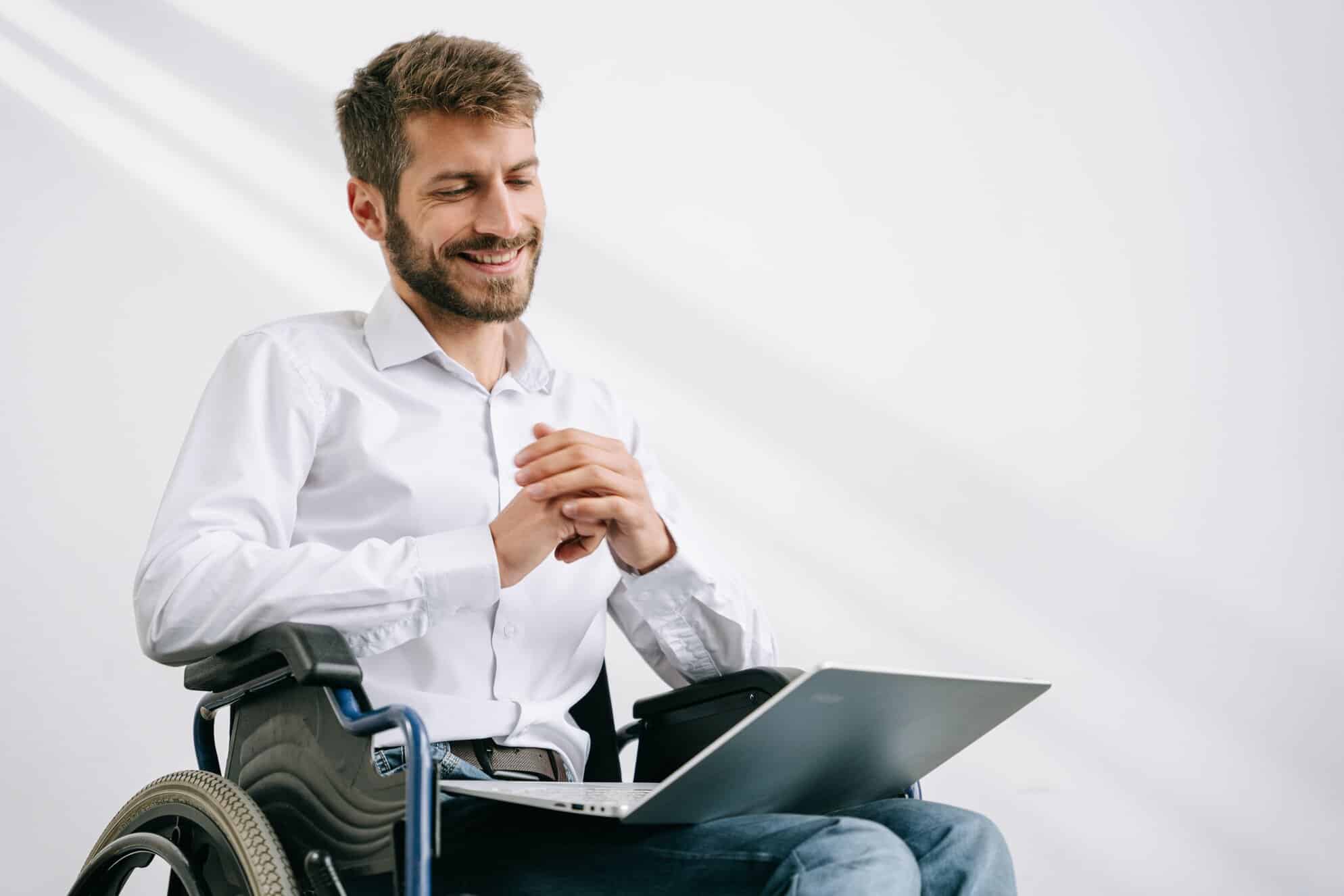 Lady with a red jacket, she is in a wheelchair looking forwards with a warm smile. She has her laptop, she is about to start a disability counselling session.