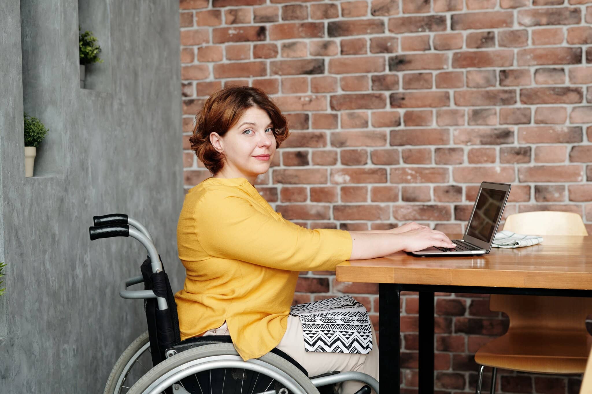 lady sat at her desk, she is looking away from her laptop. She is in a wheelchair getting ready for a spina bifida counselling session